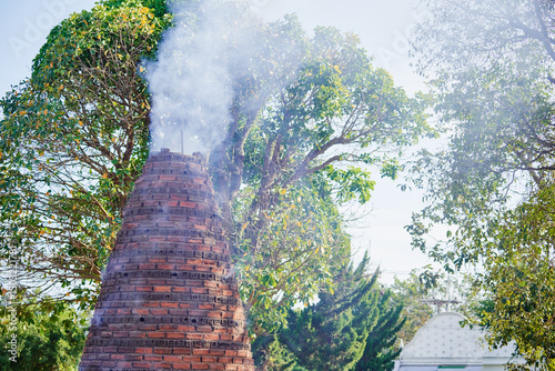 Принти на полотні Smoking Brick Kiln in Lush Greenery During a Bright Sunny Day..