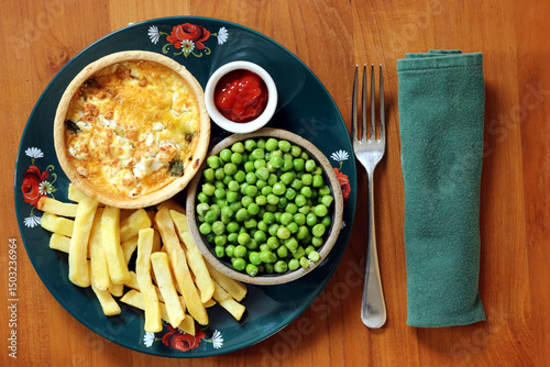 Individual egg flan with french fries and peas, served on a dark green plate.