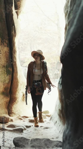 Vertical Format Video of Young traveler girl walking at rocks, woman tourist walking woods, urban scene. Woman hiker walking of mountain in sunny day