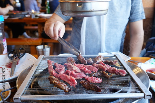 Man cooking Korean BBQ, Sliced Raw Beef Meat on Black Grill Plate - 韓国 焼肉 肉を焼く男性