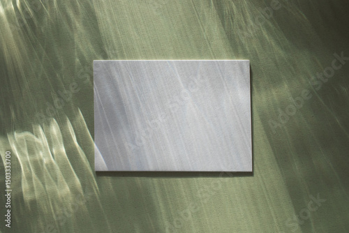 Empty paper card with sunlight shadows on glare green background. Summer abstract aesthetic mockup with caustic effects for design and presentation.