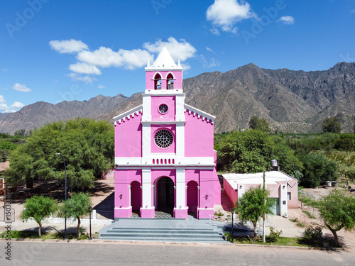 Majestic Church of Our Lady of Candelaria, Copacabana, Tinogasta. Its pink facade contrasts with the clear blue sky and imposing Catamarca mountains, an icon of the Adobe Route and Andean faith.