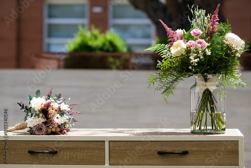 Ramo de flores preservado junto a un ramo de flores natural encima de una mesita en una celebración de boda