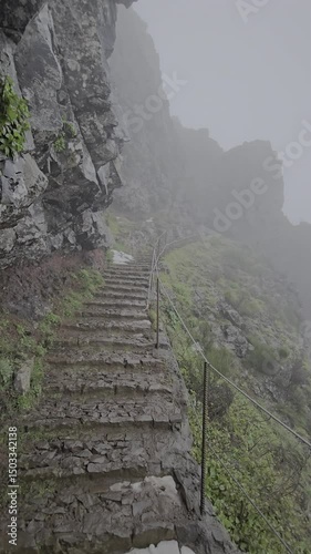 A mist-covered stairway winds along rugged peaks on the Pico Arieiro to Pico Ruivo trail in Madeira. The climb offers raw volcanic scenery and total mountain isolation.