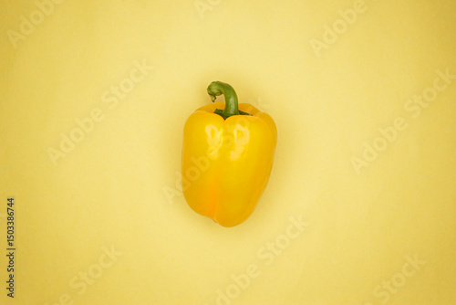 Flat lay photo of one sweet yellow Bulgarian pepper on the yellow background central composition with copy space.