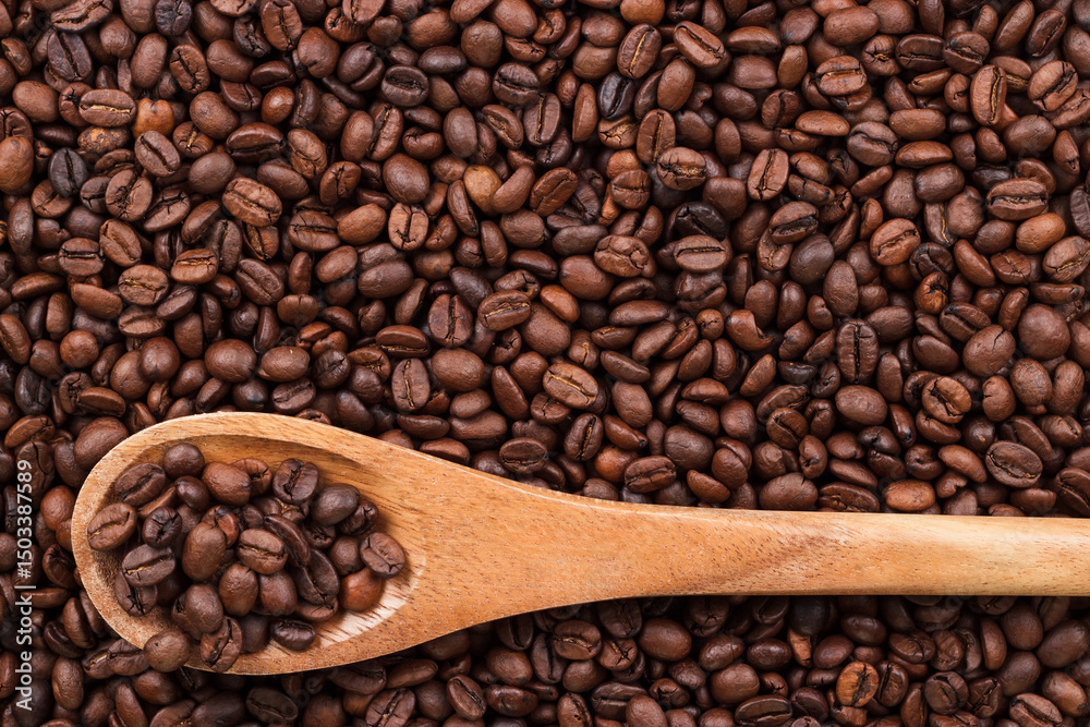 Fototapeta premium Top view of roasted coffee beans and wooden spoon on the table background