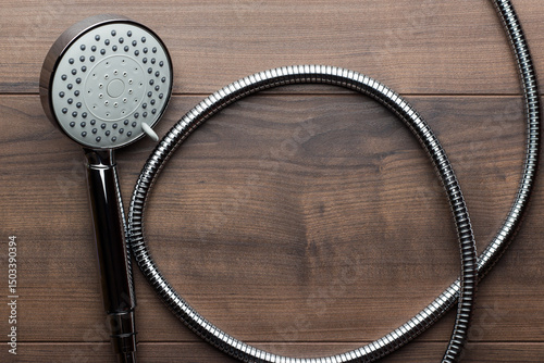 Flat lay photo of new shower head with hose on the wooden table. Top view of hand shower with copy space.