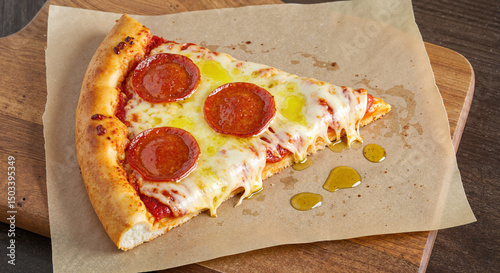Top-down view of slice of pepperoni pizza with cheese pull and oil droplets, served on parchment over wooden surface, indulgent fatty food 