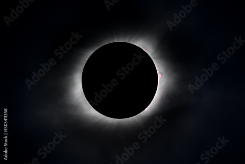 Solar eclipse  at totality seen through clouds with the corona and flares visible