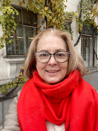 Smiling happy senior woman wearing eye glasses taking selfie outdoors