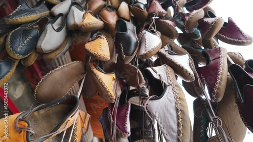 Traditional Turkish leather shoes or slippers are on display. These handmade shoes made of natural leather in different colors attract attention with their sewing details and simple designs.