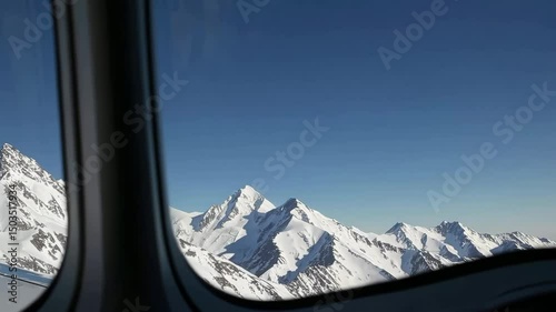 Aerial journey over majestic snowcapped mountain range through airplane window