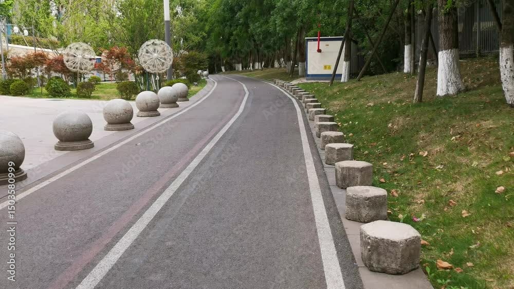 A winding asphalt road between two row of large granite boulders , acting as a barrier to block car traffic.