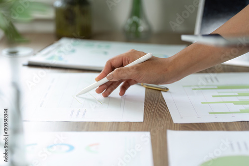 Sustainability and Data Analysis. A close-up of a hand sketching sustainable growth metrics on paper.