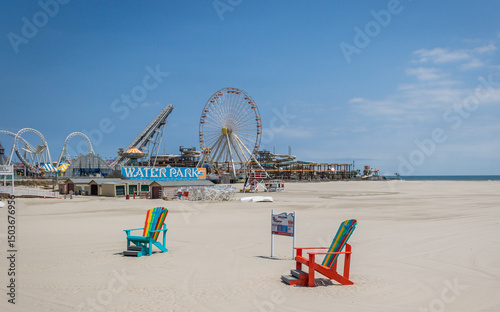 Wildwood beach giant adirondack chairs with ferris wheel and rides pre-season on a bright sunny day 