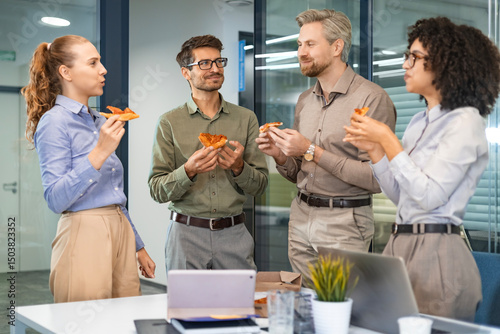 Happy multiracial colleagues have fun at lunch break in office. Excited workers celebrate shared win ordering takeaway pizza