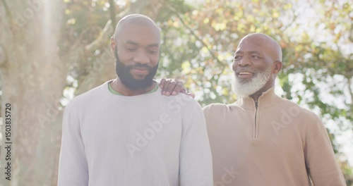 Video of happy senior african american father and adult son talking in garden