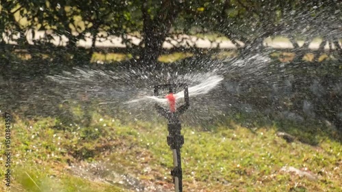 A footage of water sprinkler, spraying water at the garden.