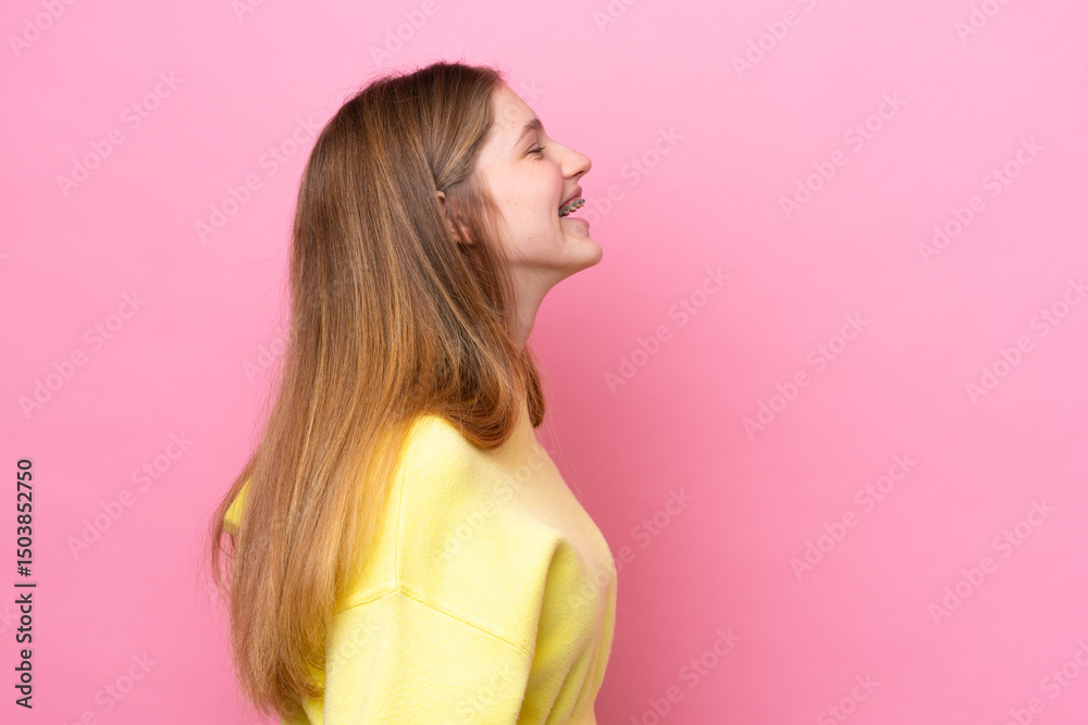 Teenager Russian girl isolated on pink background laughing in lateral position Teenager Russian girl isolated on pink background laughing in lateral position