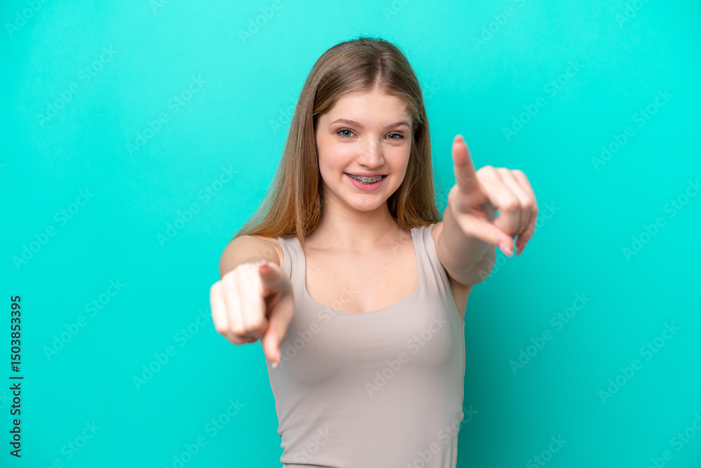 Fototapeta premium Teenager Russian girl isolated on blue background pointing front with happy expression
