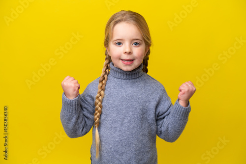 Little caucasian girl isolated on yellow background celebrating a victory