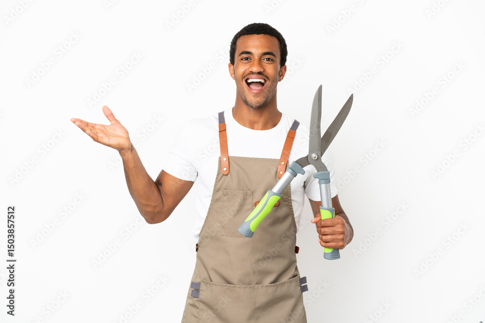 African American gardener man holding pruning shears over isolated white background with shocked facial expression African American gardener man holding pruning shears over isolated white background with shocked facial expression
