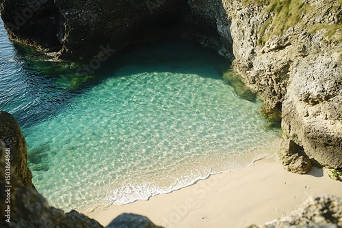 Serene turquoise waters meet sandy beach enclosed by rocky cliffs on a sunny day create idyllic scene