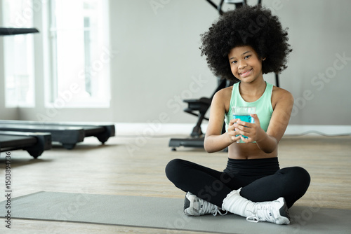 Portrait African American kid girl drinking energy drink at fitness gym	
