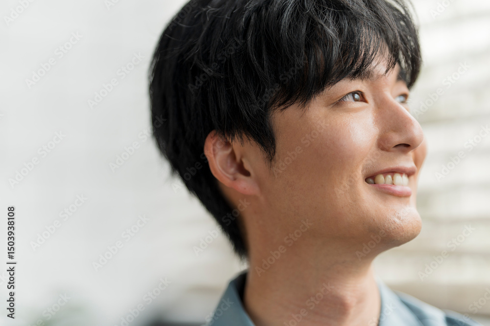 Obraz premium 微笑んでいる若い日本人男性の横顔。