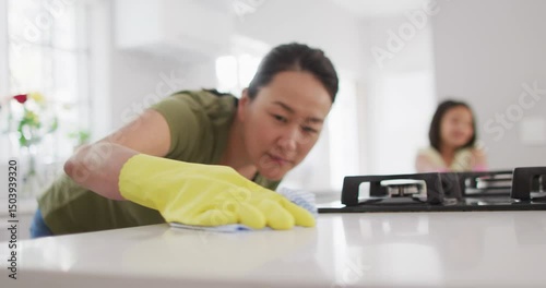 Video of happy asian mother and daughter cleaning kitchen