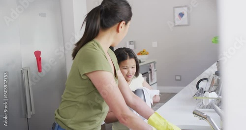 Video of happy asian mother and daughter cleaning kitchen