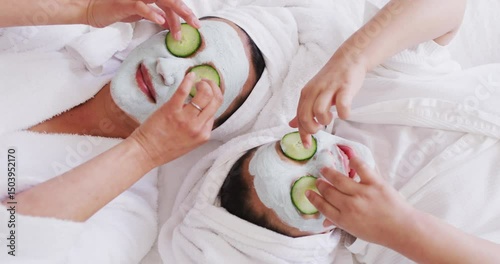 Video of happy asian mother and daughter in robes doing cucumber mask and having fun