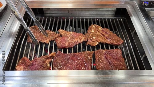 Grilling a raw beef on a charcoal grill on a table of a Korean barbecue restaurant in South Korea 