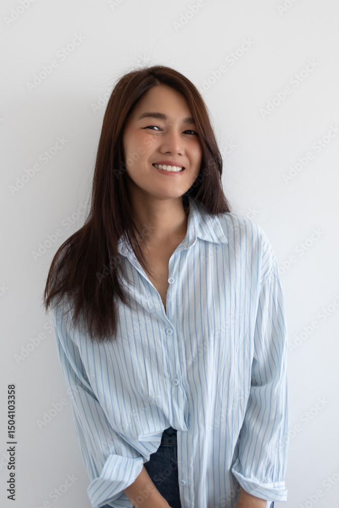 Asian woman in striped shirt smiling naturally, standing isolated over white background wall. Asian woman in striped shirt smiling naturally, standing isolated over white background wall.