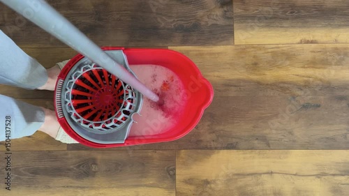 
Woman squeezing mop water in bucket to mop the floor of the house. Top view.