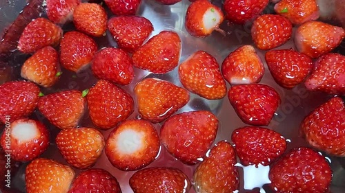 Fresh red strawberries without leaves washed in a bowl of water