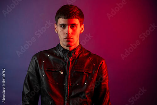 Foto Young man with dual colored lighting posing in studio setting