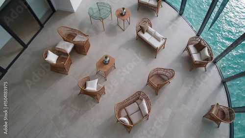 Coastal lounge area with wicker chairs and panoramic ocean view through curved glass

