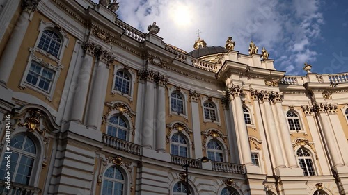 Baroque palace facade with golden accents and ornate windows under dramatic sky

