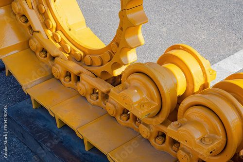 Konstfotografi Close-up of yellow heavy machinery track and rollers, showing the metal components of a crawler system for construction or mining equipment