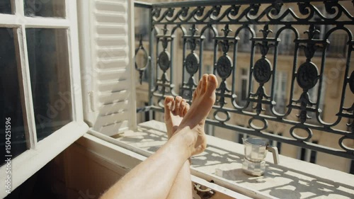 Woman relaxing with feet up on balcony railing, enjoying cityscape view
