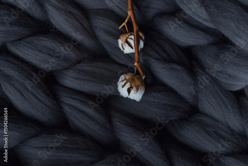 a branch of cotton on a background of a gray merino wool blanket