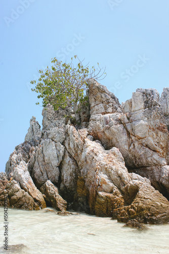 Scenic view of a stunning limestone rock island rising from the turquoise waters of Thailand. Exotic tropical seascape with dramatic cliffs, lush greenery, and crystal-clear ocean