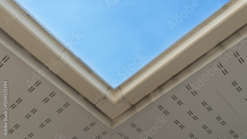 Under view of rooftop. White PVC eaves and drainage channels. background of blue sky.