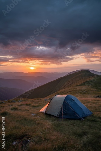 Sunset Over Mountains With a Tent Set up in a Grassy Field Showcasing Natures...