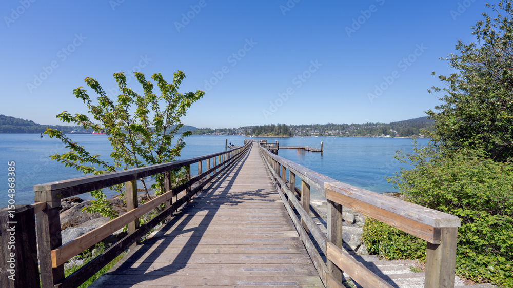 Obraz premium Wooden pier leading to fishing platform at Belcarra public park, BC, Canada, with stunning views across Burrard Inlet to town of Deep Cove.