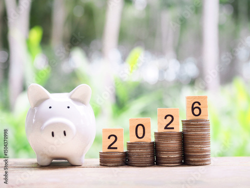Piggy bank, Wooden blocks with the number 2026 on stack of coins. The concept of saving money, Financial, Investment and Business growing in year 2026.