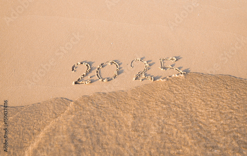 2025 year handwritten on the beach in the sunset time. New Year 2025 concept