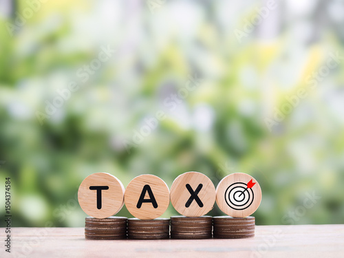 Wooden blocks with the word TAX on stack of coins. The concept of saving money for payment tax in future
