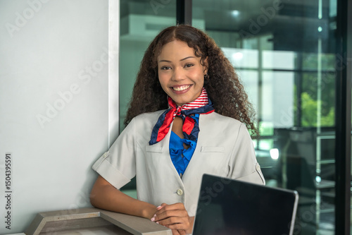 Friendly female airline ground crew working at airport check in registration desk